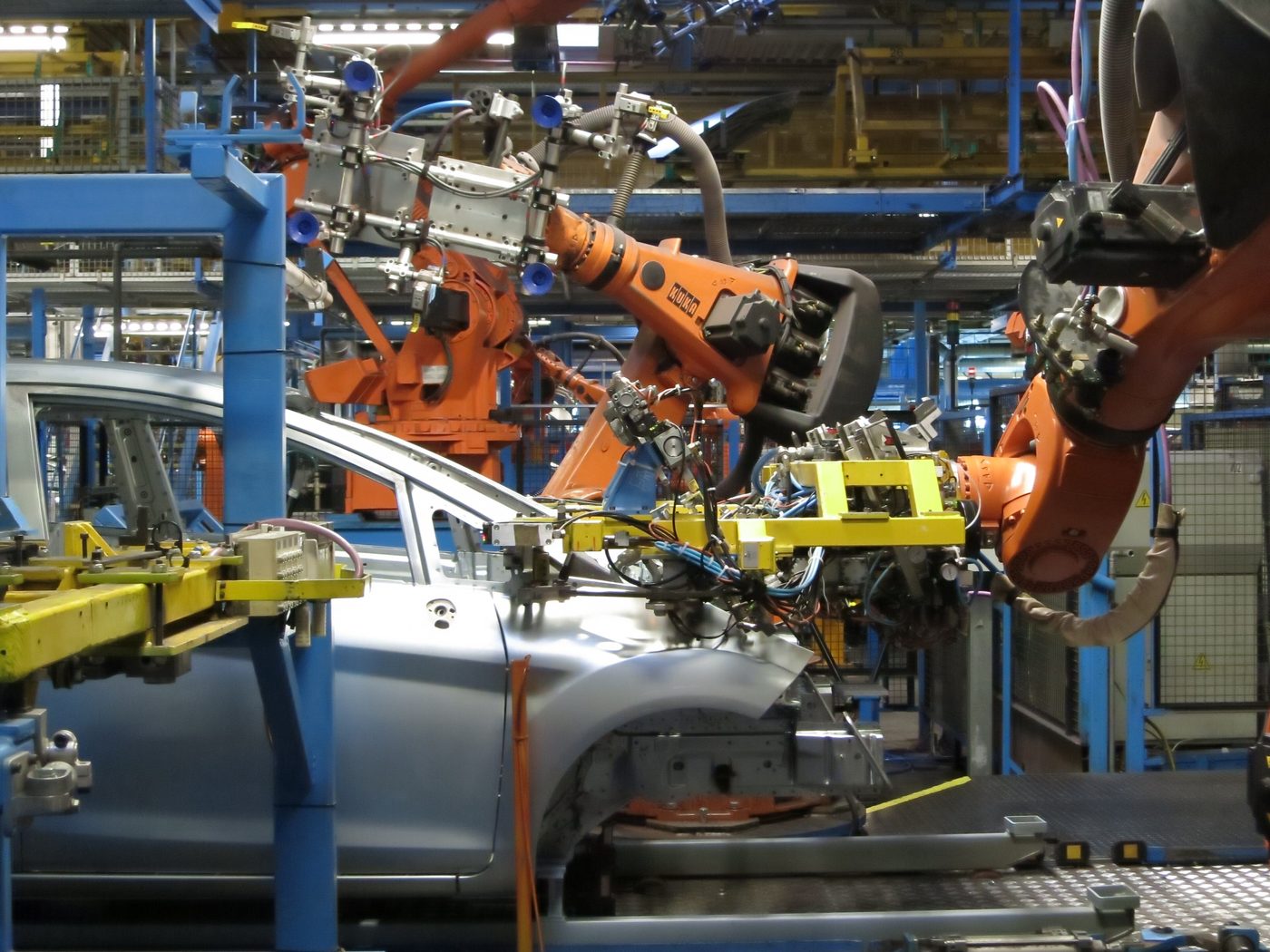 Des bras robotisés industriels soudant des caisses automobiles sur une chaîne de montage Ford à Cologne